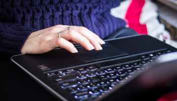 A person using a black laptop computer