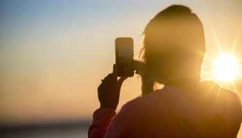 Taking a photograph of a sunset using a phone.