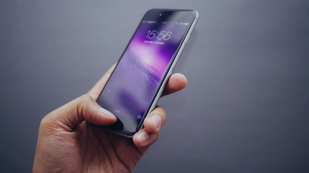 Hand holding an iPhone. Avoid using too much cellular data with Wi-Fi Assist