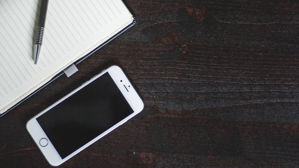 iPhone on a desk with a notepad and pen