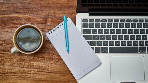 Apple MacBook computer, notepad and coffee cup on a table