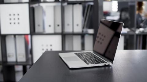 Apple MacBook on a table in an office. Make sure it connects to the right Wi-Fi network