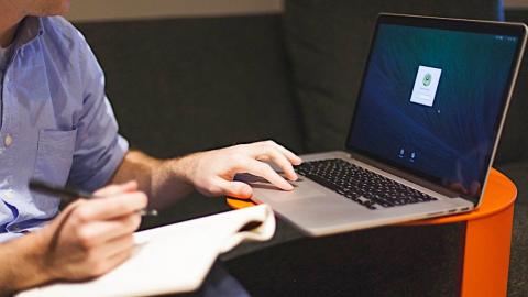 Man using an Apple MacBook laptop computer and a notepad