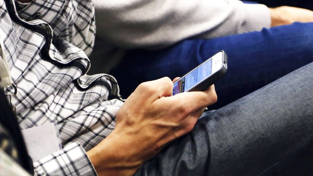 Sitting man using an iPhone.