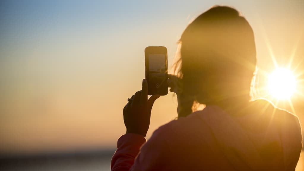 Taking a photograph of a sunset using a phone.